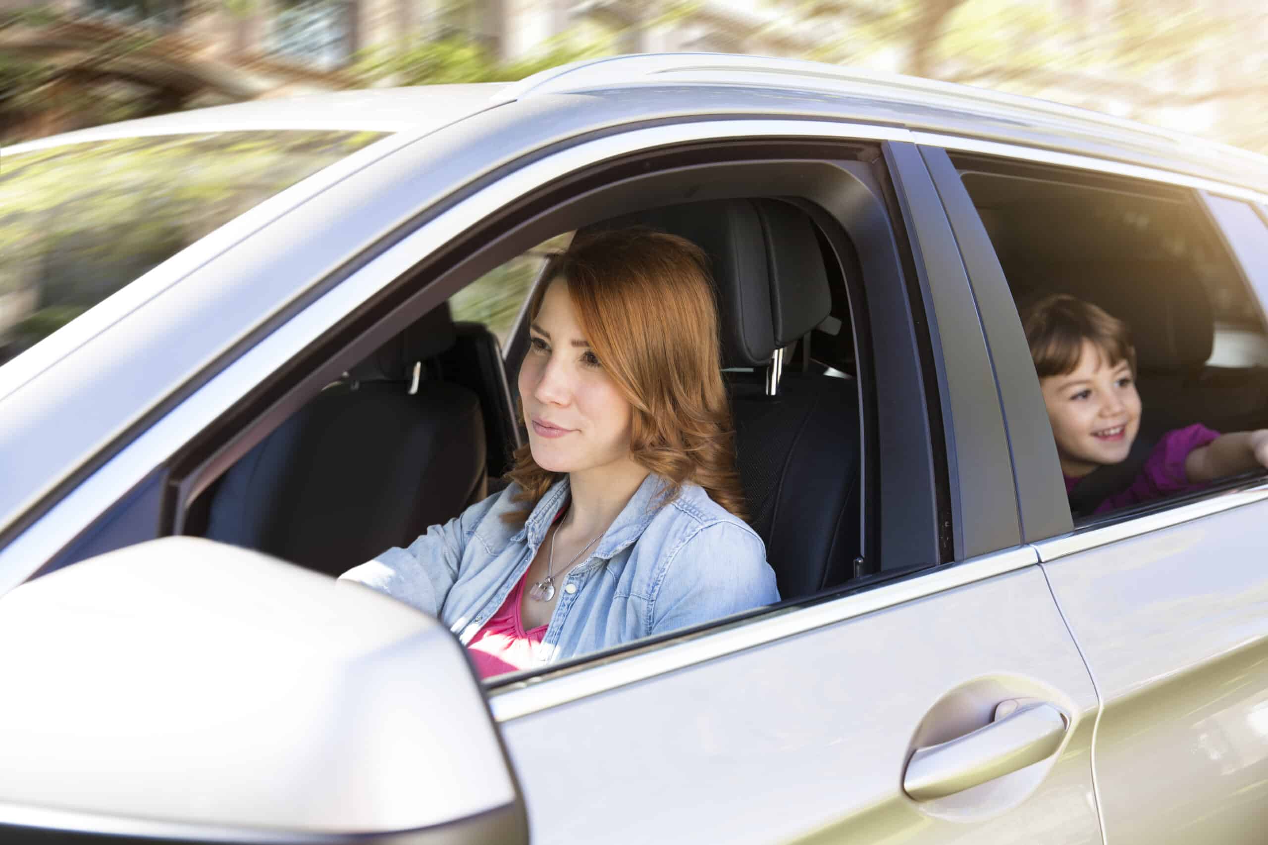 Woman driving car with girl on backseat